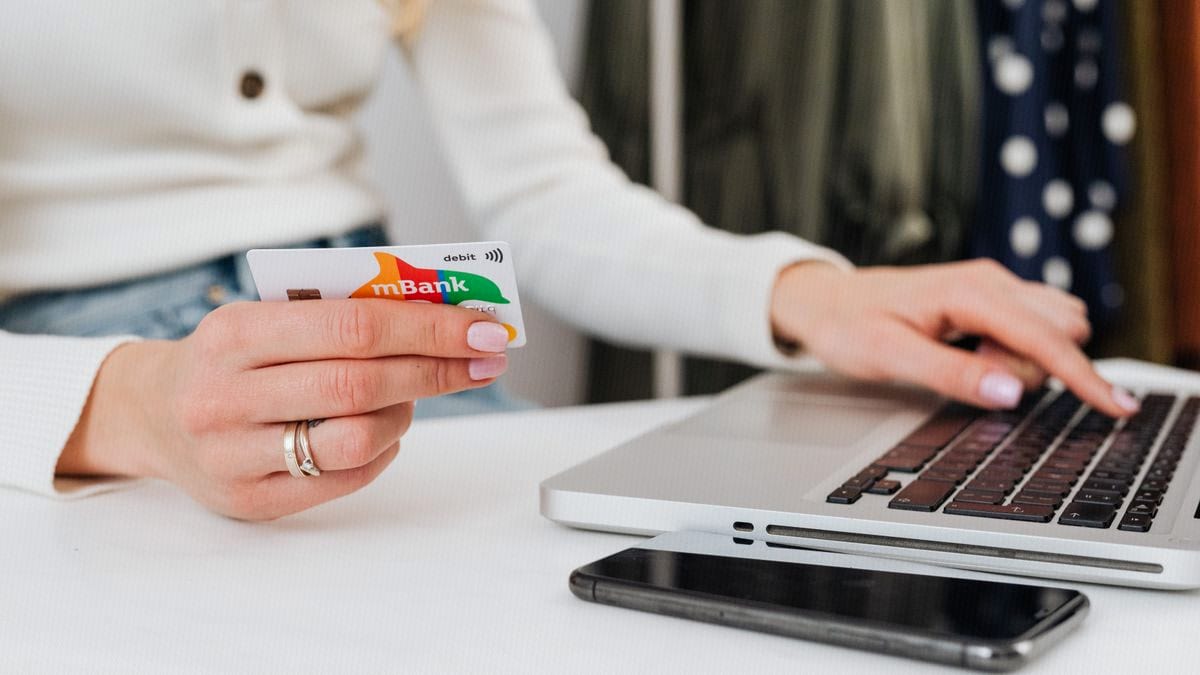 A debit card held over a laptop — the download-wall moment billed builders sell as free