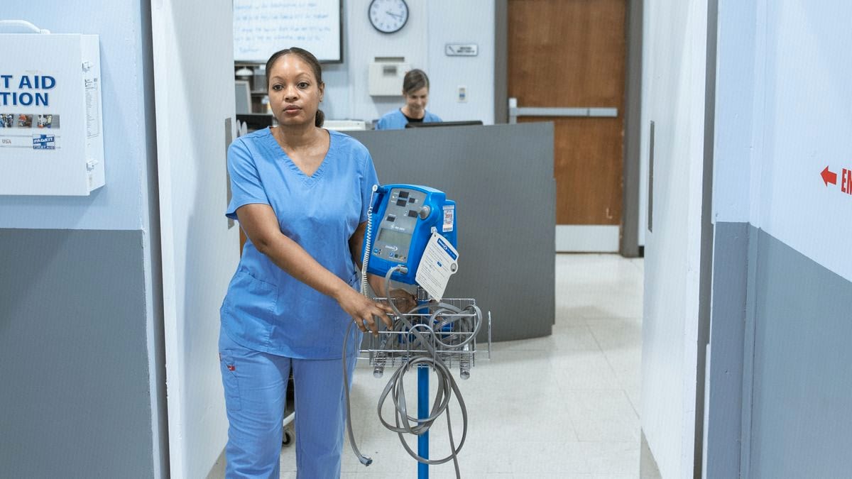 A nurse in scrubs walking a hospital corridor, the kind of clinical work a UK CV has to make room for