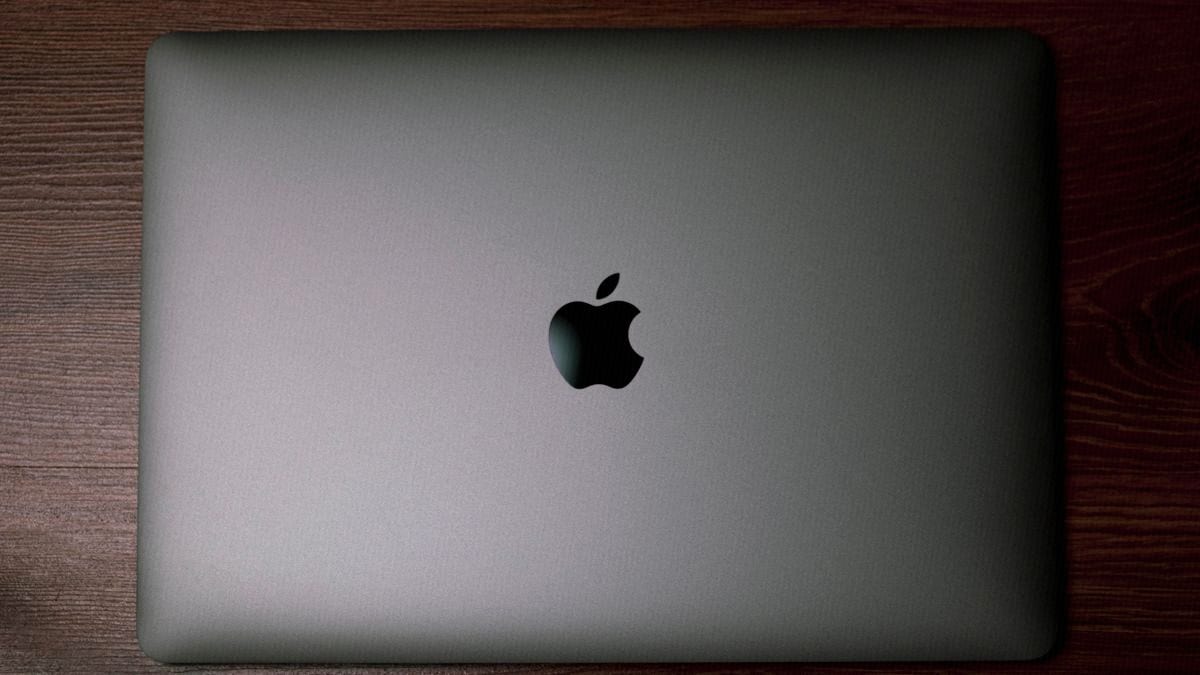 A closed laptop rests on a dark wooden desk, with no login screen in sight.